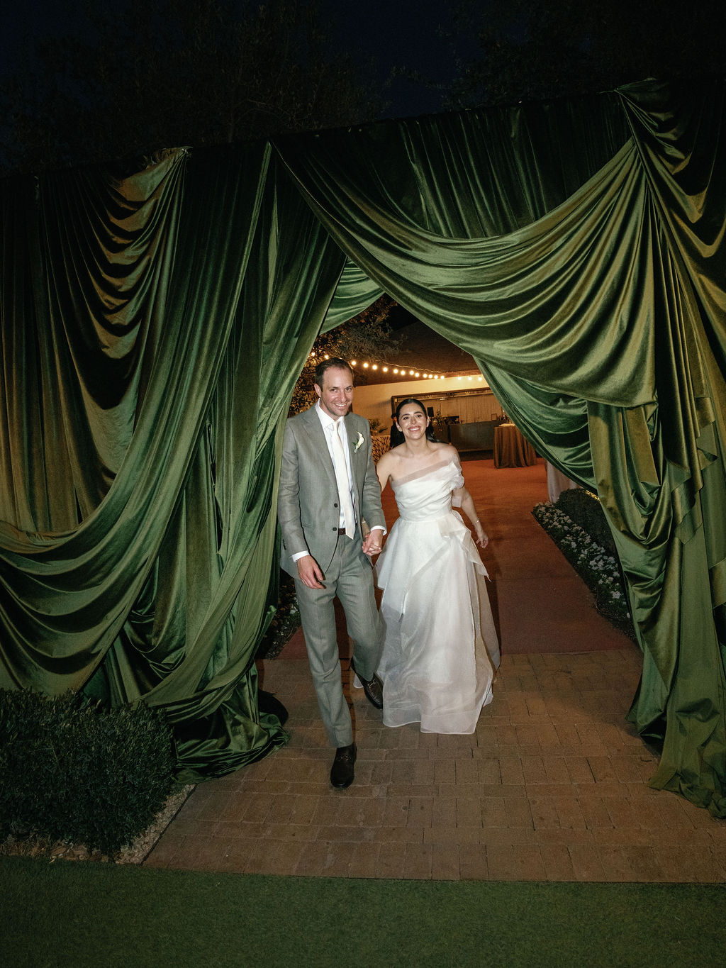 Newlyweds walking hand-in-hand into their reception at El Chorro, string lights overhead
