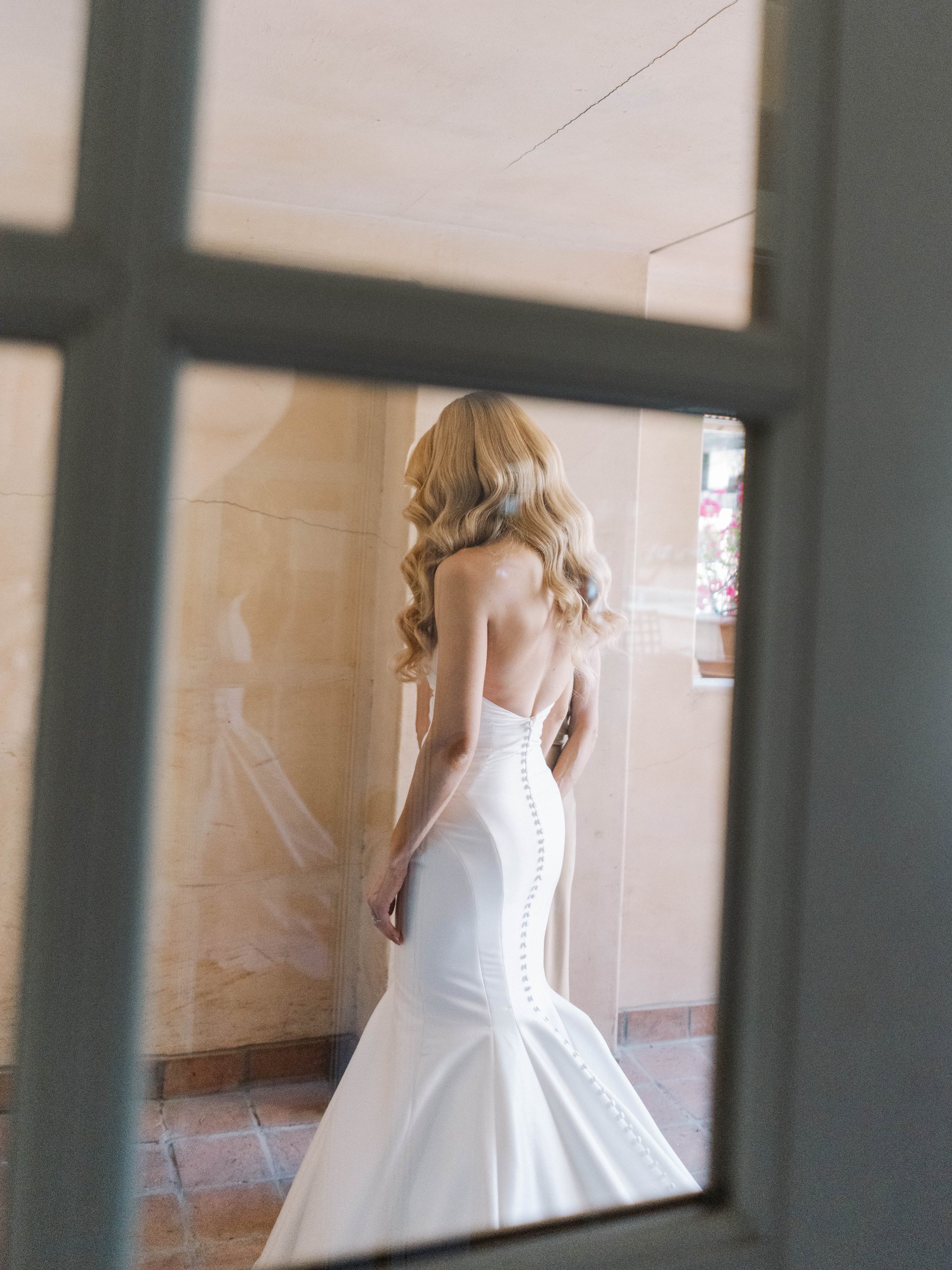 Meg seen through a window in her wedding gown