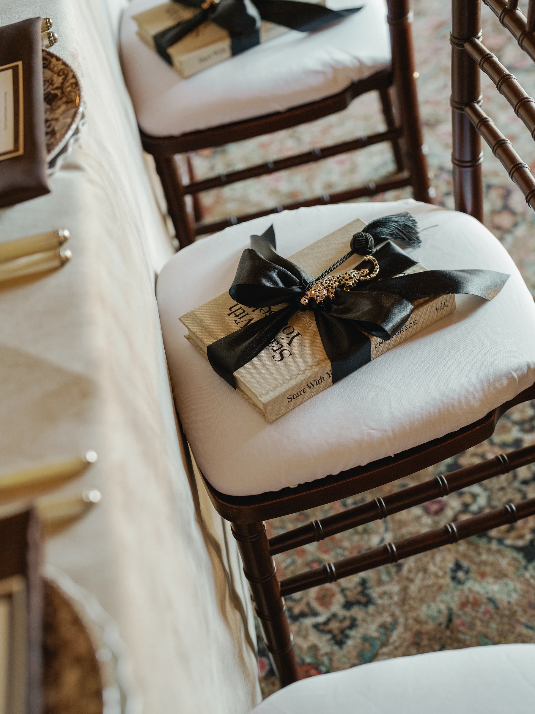 Gift book tied with black ribbon resting on a white chiavari chair cushion