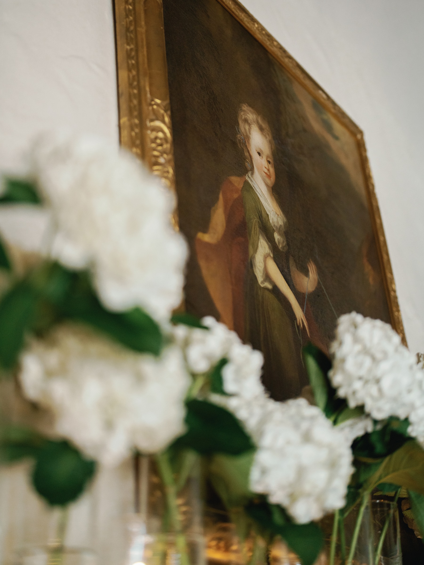 Tilted close-up of white hydrangea beneath an oil portrait