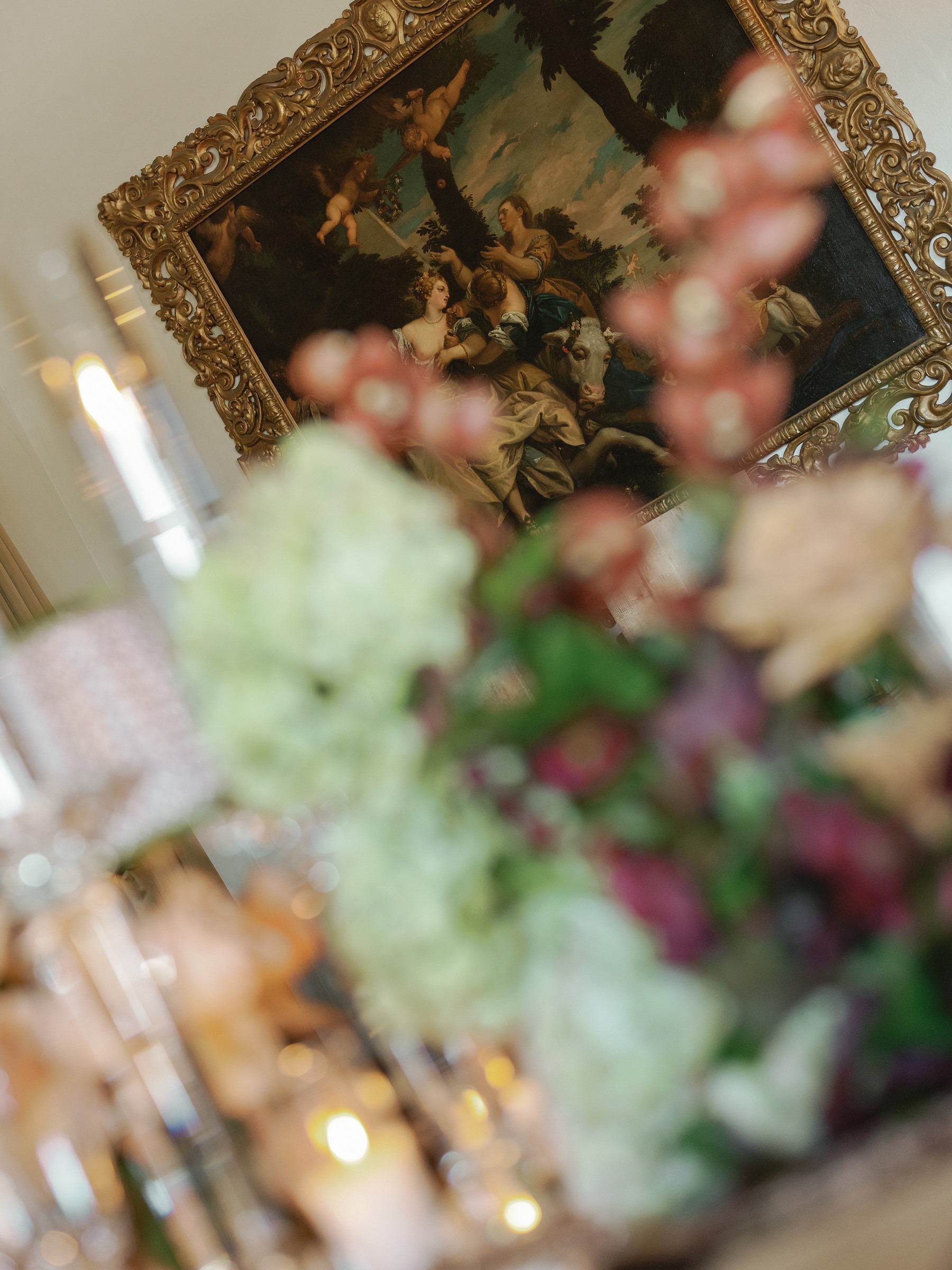 Blurred, tilted close-up of burgundy and green florals beside a gold frame
