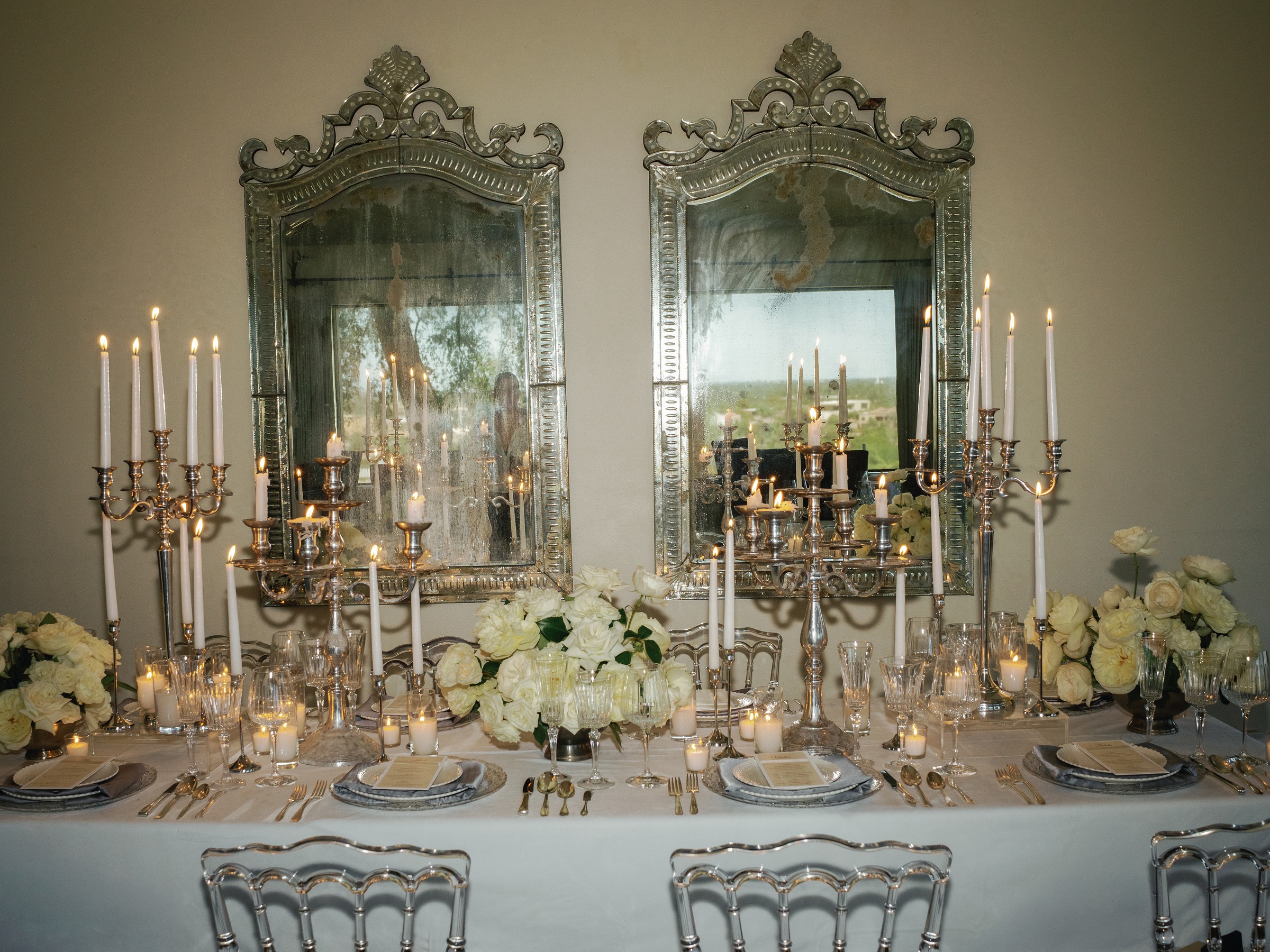 Mirror-lined dining room with silver candelabras and white roses on a long dinner table, Wrigley Mansion Phoenix