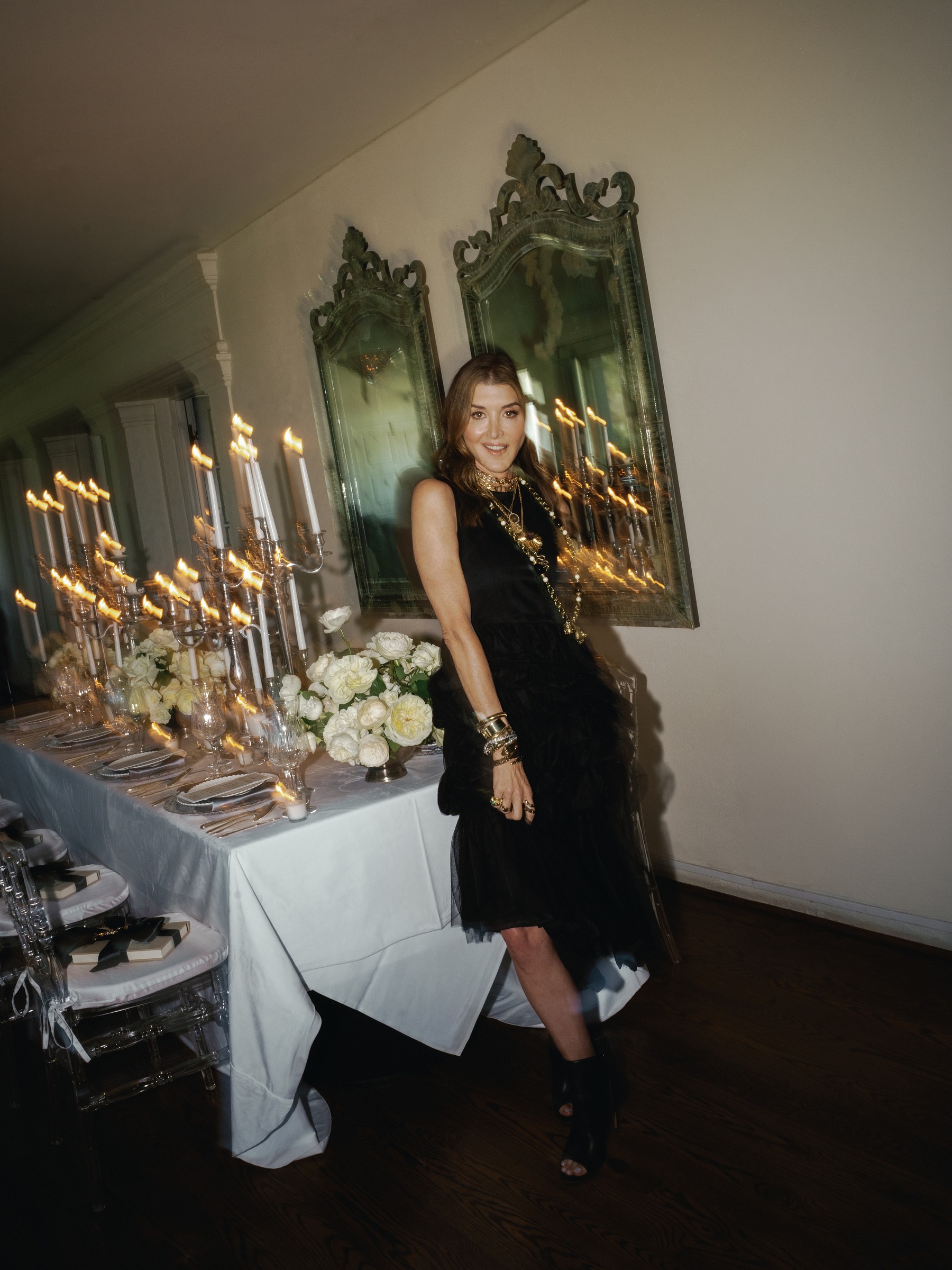 Catherine Tuton leaning at the candlelit table in front of two antique mirrors with soft trails of golden light